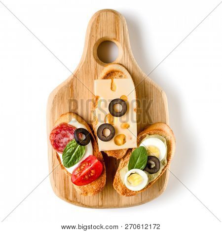 Open faced sandwich canape or crostini on a wooden serving board isolated on white background closeup. Top view.