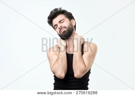 Young Hispaniv Man With Berad In Black Clothes Having Pain In Neck