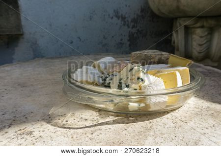 Assorted Various Types Of Delicious Cheese In Glass Plate On Stone Table. Vintage Style.