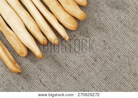 Italian Grissini Dry Breadsticks Close Up On Grey Colored Tablecloth. Food Background With Copy Spac