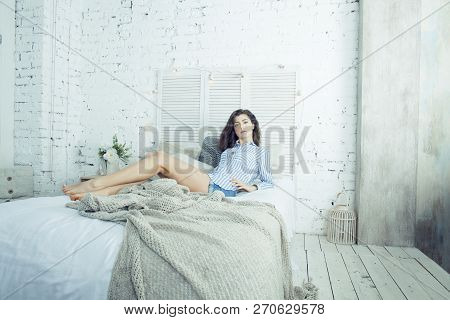 Young Pretty Brunette Woman In Her Bedroom Sitting At Window. Li