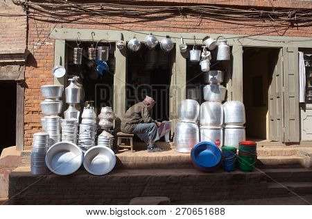 Bhaktapur, Nepal - January 23, 2017: Man Of Newari People Selling Kitchenware And Utensils In His Sh