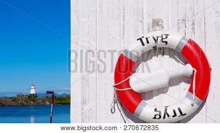 Rescue Ring In Norwegian Harbor And Seascape With Lighthouse At Hovsund Fishing Port, Gimsoya Lofote