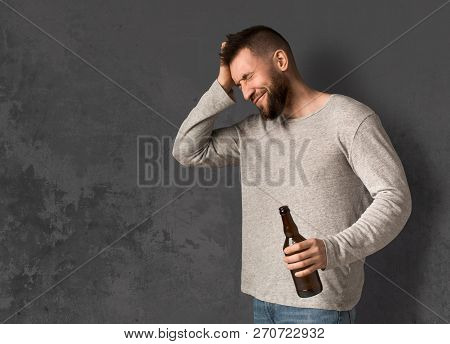 Man Suffering From Hangover With Beer Bottle, Alcohol Addiction And Consequences Concept, Copy Space