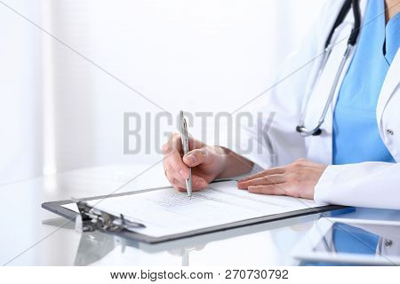 Female Doctor Filling Up Medical Form On A Clipboard, Closeup. Healthcare, Insurance And Medicine Co