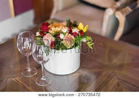 Beautiful Fresh Flowers In A Round Box And Empty Glasses Are On The Table. A Date At The Restaurant