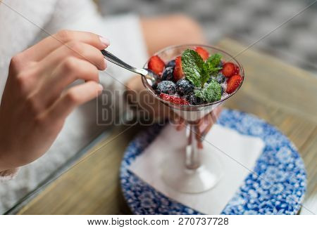 Fragment Of The Girl's Hand Close-up. The Girl Tries A Delicious And Beautiful Dessert With Berries 
