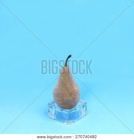 Frozen Pear On Ice Cube On Blue Background. Creative Concept: Quickly Frozen Fruits And Vegetables R