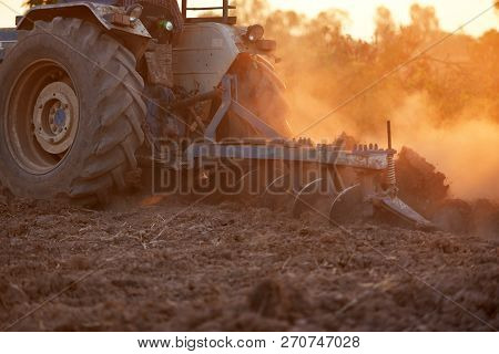 Agriculture Harrows Disc Harrows Covered In Muddy Fields Behind The Sunset.