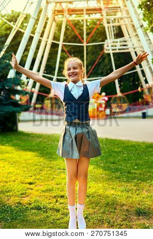 Schoolgirl In Uniform Joyful Smiling And Jumping Raising Hands Up. A Satisfied Student Is In A Good 