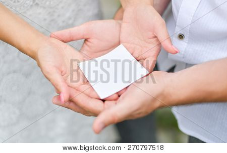 A Small Blank Piece Of White Paper Rests In The Palms Of Men And Women