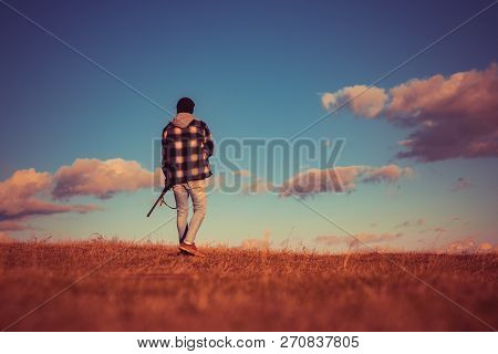 Illegal Hunting Poacher In The Forest. Rifle Hunter Silhouetted In Beautiful Sunset. Autumn Hunting 