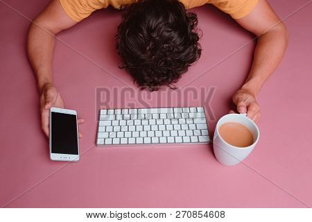 Handsome Curly Brunette Man Lying On A Pink Table Nearly Dead   From Creating Content. He Is Holding