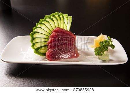 Sashimi With Tuna In A White Plate. On A Black Background.