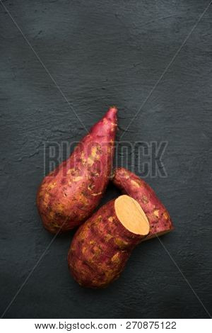 Raw orange sweet potatoes on dark background, Top view close up.