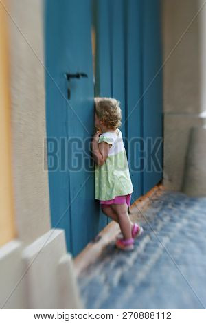 The Child Watches Through The Blue Door Slit