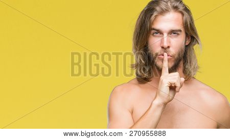 Young handsome shirtless man with long hair showing sexy body over isolated background asking to be quiet with finger on lips. Silence and secret concept.