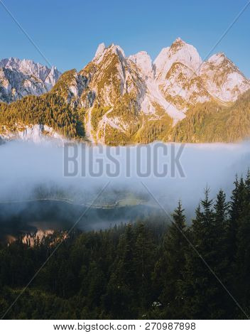 Great morning on the alpine lake Vorderer Gosausee. Picturesque foggy valley. Location place famous resort Salzkammergut, Gosau valley, Austrian alps. Dachstein glacier. Discover the beauty of earth.