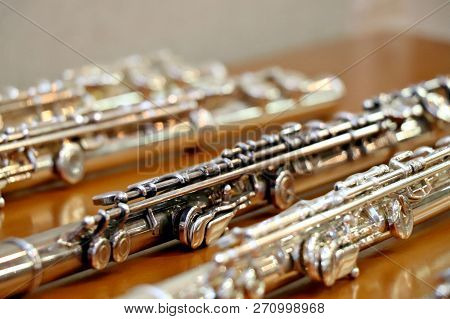 Blurry Soft Focused Set Of Silver Flutes On The Wooden Table Close Up. Musik Background. Selected Fo