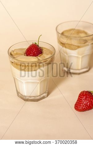Dalgon Coffee In A Transparent Glass With Milk On A Pastel Background With Strawberries.