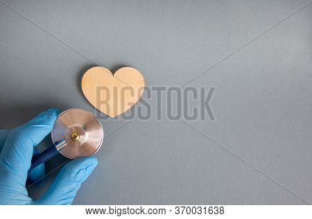 Wooden Heart, Hand In Blue Glove With Stethoscope On Blue Background. Medical Concept. Beautiful Blu