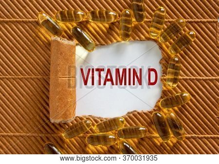 The Text 'vitamin D' Appearing Behind Torn Brown Paper. Yellow Pills.