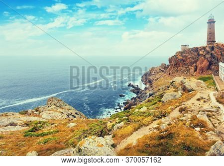 Toned Photo With The Lighthouse On The Rocky Coast. Galicia, Spain