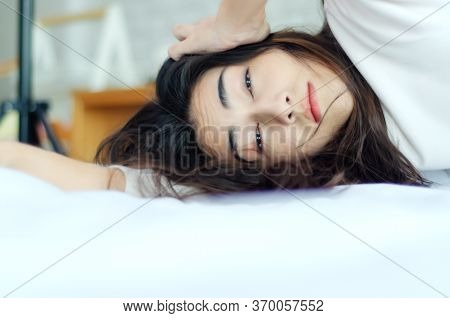 Asian Woman Is In A White Bedroom. She Is Sleepy.a Girl On The Bed.
