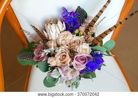 Stylish Wedding Bouquet With Feathers On A White Leather Chair.