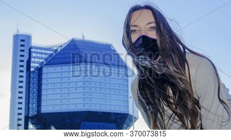 Portrait Of Brunette Woman In A Protective Medical Mask On A Cityscape Background. Virus Protection.