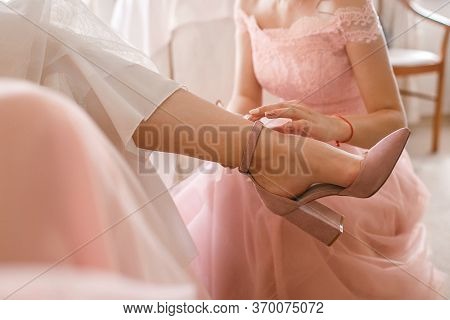 A Girlfriend Helps A Bride To Put On Her Wedding Shoes. Beautiful Female Feet Closeup