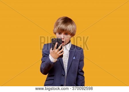 A Surprised Boy With His Mouth Open Looks Into His Phone.