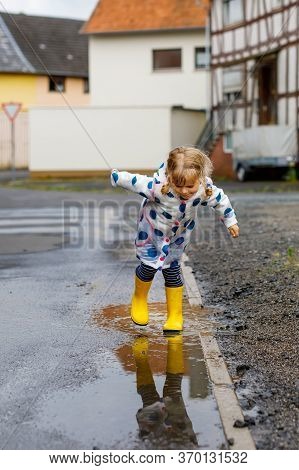 Little Toddler Girl Wearing Yellow Rain Boots, Running And Walking During Sleet On Rainy Cloudy Day.