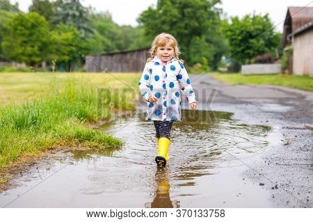 Little Toddler Girl Wearing Yellow Rain Boots, Running And Walking During Sleet On Rainy Cloudy Day.