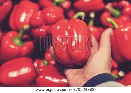 A Man Chooses Red Bell Peppers In A Grocery Store, At The Market. Hand Take The Pepper From A Vegeta