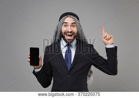 Excited Arabian Muslim Businessman In Keffiyeh Kafiya Ring Igal Agal Suit Isolated On Gray Backgroun