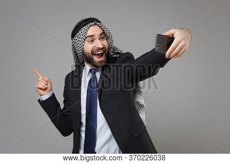 Excited Arabian Muslim Businessman In Keffiyeh Kafiya Ring Igal Agal Suit Isolated On Gray Backgroun