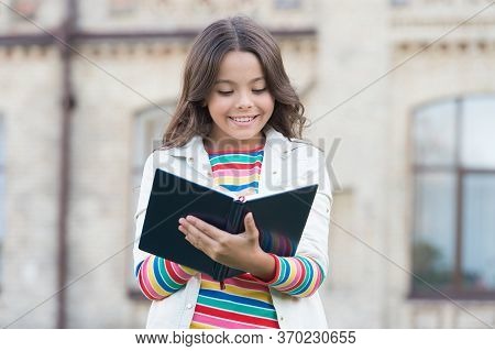 Little Girl Hold Book. Girl With Book School Building Background. Book From Library. Making Notes. I