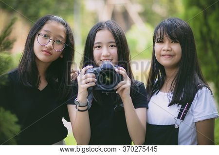 Group Of Asian Teenager Relaxing In Garden With Dslr Camera In Hand