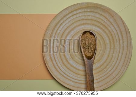 Guarana Powder In A Wooden Spoon And A Bamboo Plate On A Yellow-orange Pastel Background. Natural En