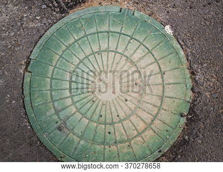 Green Manhole. Manhole Cover On Asphalt Street.
