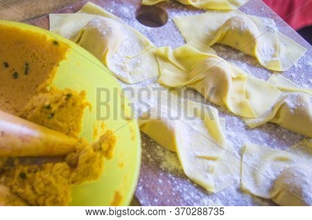 Hand Of The Italian Housewife Prepares The Egg Pasta, Ravioli And Tortelli, Stuffed With Pumpkin Fil