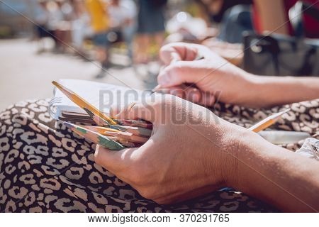 Artist While Drawing In The Open Air, Hand Holding A Few Colored Pencils In The Light Of The Sun On 