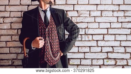 Guy In A Classic Suit With An Umbrella On A Brick Wall Background