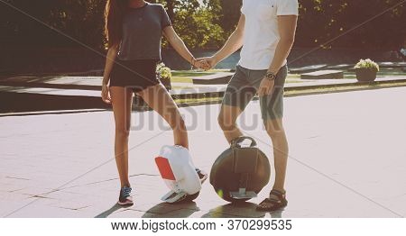 Young Couple Driving On Monowheel In The Park