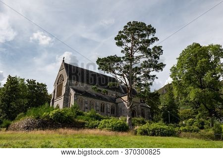 Ancient Saint Mary & Saint Finnan Catholic Church On A Hill With A Tree In Glenfinnan, Scotland, Uk