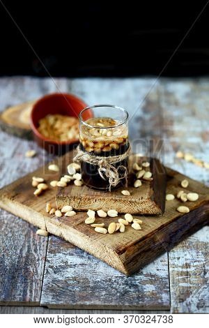 Selective Focus. A Glass Of Black Soda Drink And Peanuts. Salted Peanuts In A Glass With Coke. Ameri
