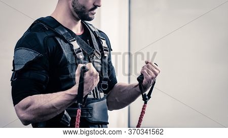 Young Athletic Man In Ems Fitness Vest Doing Exercises With Expander