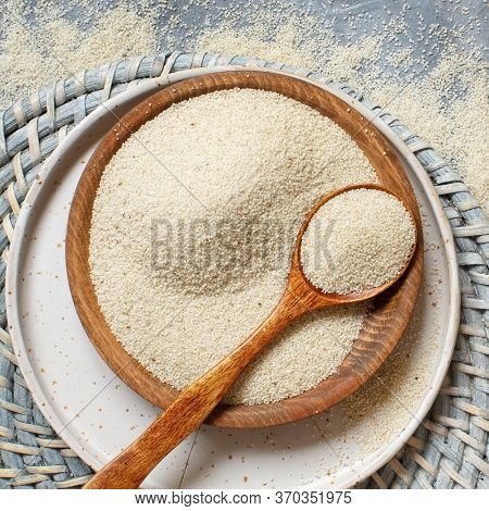 Raw Uncooked Fonio Seeds With A Spoon On A Plate On Grey Background  Top View