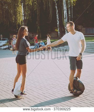 Young Couple Driving On Monowheel In The Park